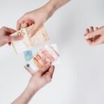 Close-up of hands exchanging euro banknotes, symbolizing currency trade and financial transactions.